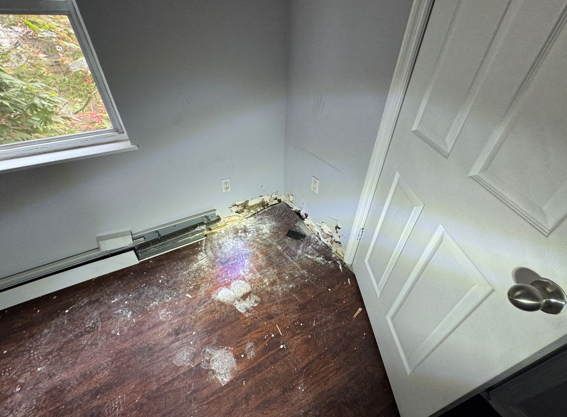 Bedroom corner with damaged wall base